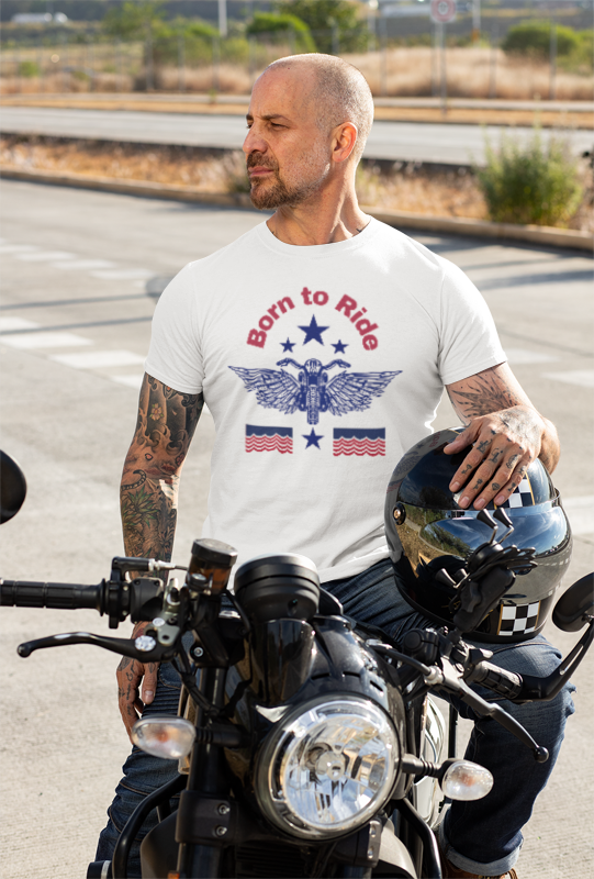 Man wearing a 'Born to Ride' t-shirt on a motorcycle with a scenic background.